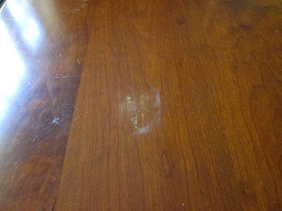 Damage from a hot plate placed on the table top without a trivet. Damage from a hot plate placed on the table top without a trivet.